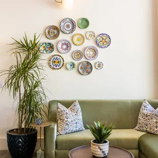 a living room with a green couch and decorative plates on the wall