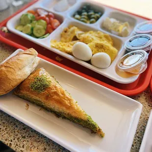 Pistachio Baklava, Omelette with Turkish sausage, boiled eggs, Mixed veggie plate, olives, Peynir (Cheese) Tost, honey, jam, Nutella