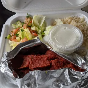 Doner Kabab with bread (underneath) in tomato sauce with salad, rice and yogurt sauce