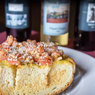 a white plate with a hot dog and a bottle of wine