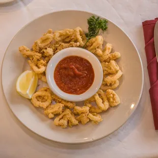 a plate of fried calamails with a side of tomato sauce