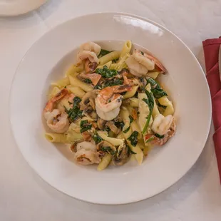 a plate of pasta with shrimp and spinach