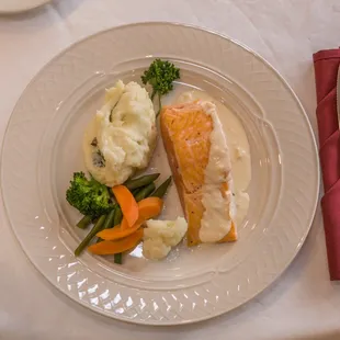 a plate of fish, mashed potatoes, carrots, and broccoli
