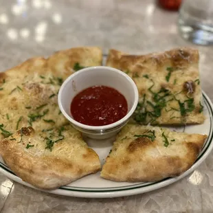 a white plate with four pieces of pizza and a small bowl of ketchup