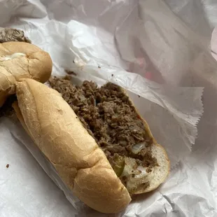 Nasty cheesesteak sandwich with raw veggies.