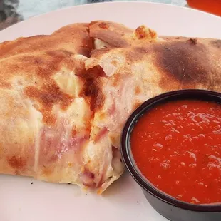 a plate of pizza and a bowl of tomato sauce
