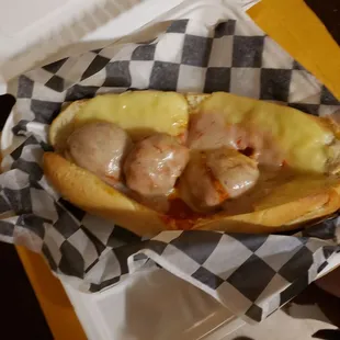 a hot dog with meatballs and cheese