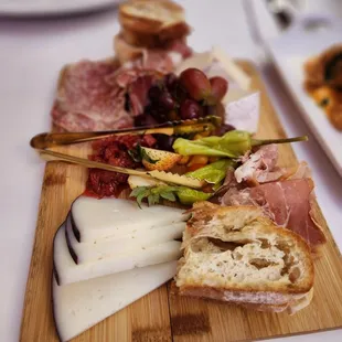 a variety of meats and cheeses on a cutting board
