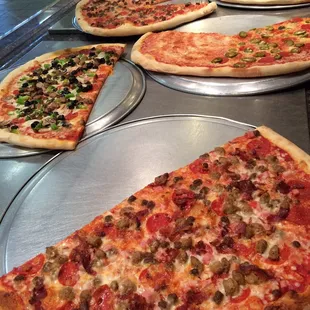 a variety of pizzas on pans