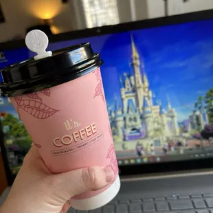 a person holding a coffee cup in front of a laptop
