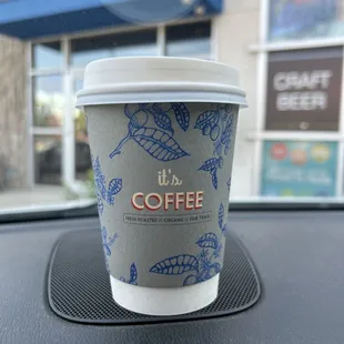 a cup of coffee on the dashboard of a car