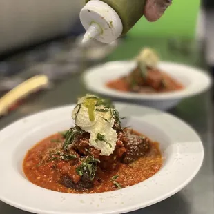 a person sprinkling sauce on a dish