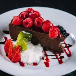 a piece of chocolate cake with raspberries and whipped cream