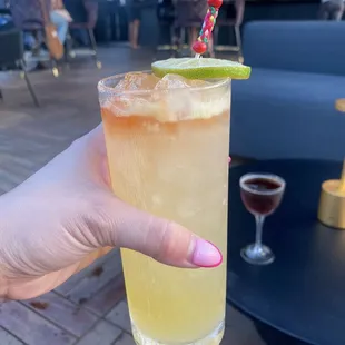 a hand holding a glass of a drink