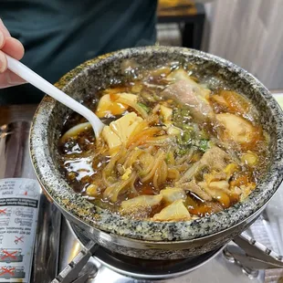 a person stirring up a bowl of soup