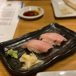 two pieces of sushi on a black plate