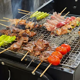 a variety of meat and vegetables cooking on a grill