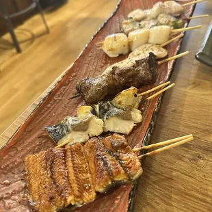 Assorted yakitori. Bottom to top: unagi/eel, mackerel, beef short rib, chicken tender, scallops, pork wrapped asparagus, and chicken thigh.
