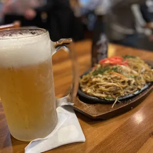 a glass of beer and a plate of noodles