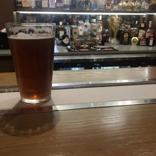 Flat beer on frost rail and bartender's neat lab in background.