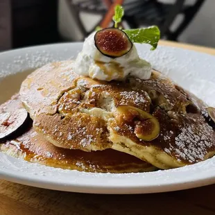 a plate of pancakes with whipped cream and figs