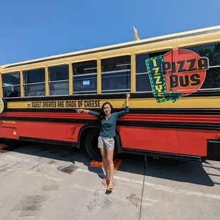 a woman standing in front of a pizza bus
