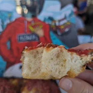 a hand holding a piece of pizza