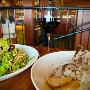 two plates of food and a glass of wine