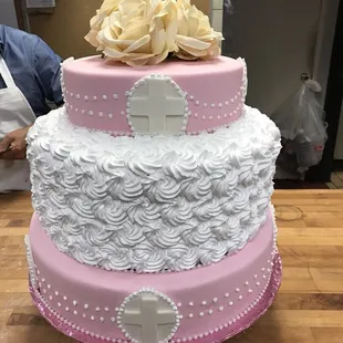 a pink and white cake with a cross on top
