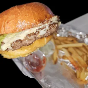 Cheeseburger with lettuce, ketchup, and mayonnaise with a side of French fries.