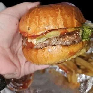 Cheeseburger with lettuce, ketchup, and mayonnaise with a side of French fries.