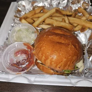 Cheeseburger with lettuce, ketchup, and mayonnaise with a side of French fries.