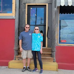  a man and woman standing in front of a restaurant