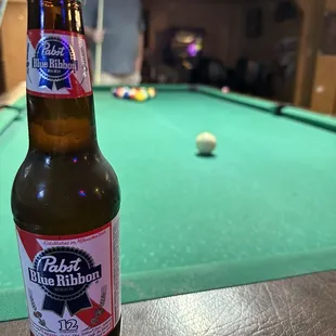 a beer bottle on a pool table