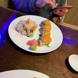 a woman looking at her phone while eating sushi
