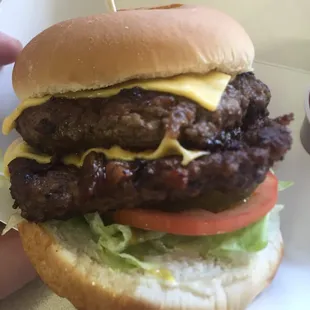 a hand holding a cheeseburger