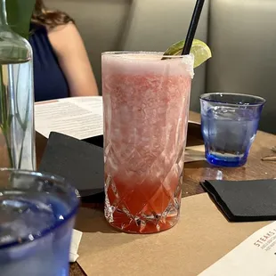 a pink drink with a lime garnish