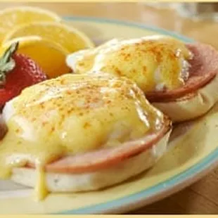 a plate of eggs benedicts with ham and strawberries