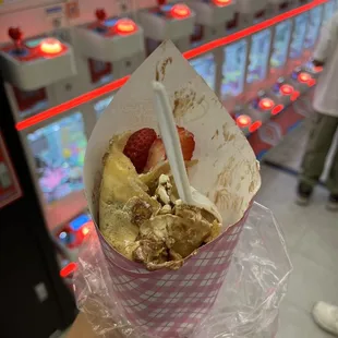 a person holding a paper cone with a strawberries on it