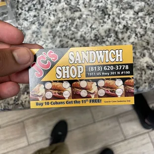 a person holding a sandwich shop card