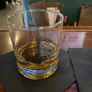 a glass of whiskey on a coaster