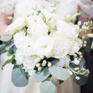 Fresh and classic bridal bouquet of white roses, white hydrangeas, white ranunculus, silver dollar eucalyptus.