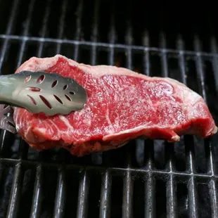a piece of steak being cooked on a grill