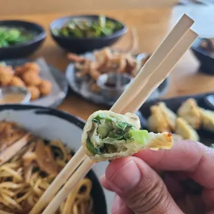 a person holding chopsticks over a bowl of ramen