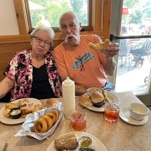 a man and woman sitting at a table with food