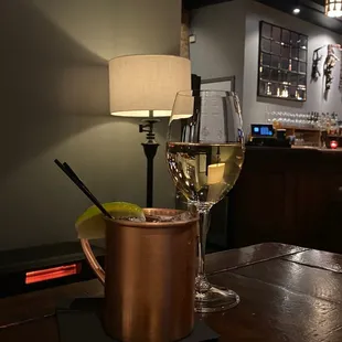 a glass of white wine and a copper pot