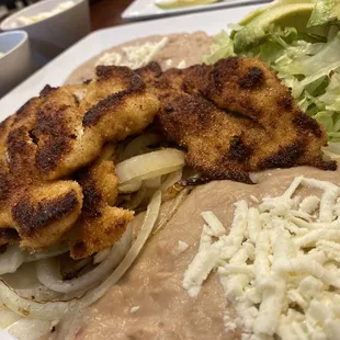 Pollo Pechuga Empanizada (breaded chicken breast) with refried beans, avocado &amp; queso fresco.