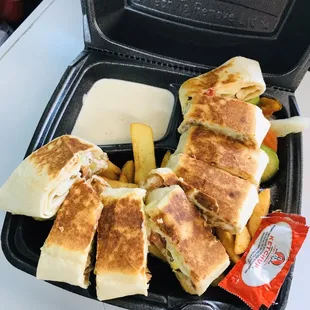 a sandwich and fries in a styrofoam container