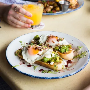 Avocado Toast at Brunch: Toasted sourdough bread, fresh smashed avocado, feta cheese, toasted pecans, balsamic reduction, sunny-side-up eggs