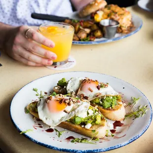 Avocado Toast at brunch: Toasted sourdough bread, fresh smashed avocado, feta cheese, toasted pecans, balsamic reduction, sunny side up eggs